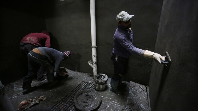 عمال يسمون جدارًا داخليًا في مبنى قيد الإنشاء في العاصمة العراقية بغداد